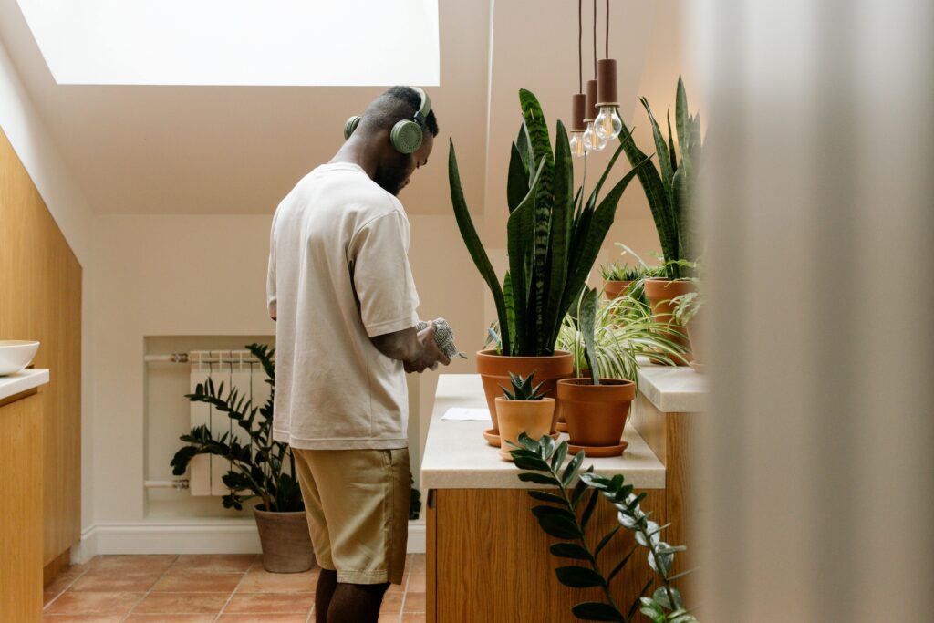 Man in Headphones Standing by Dresser with Plants